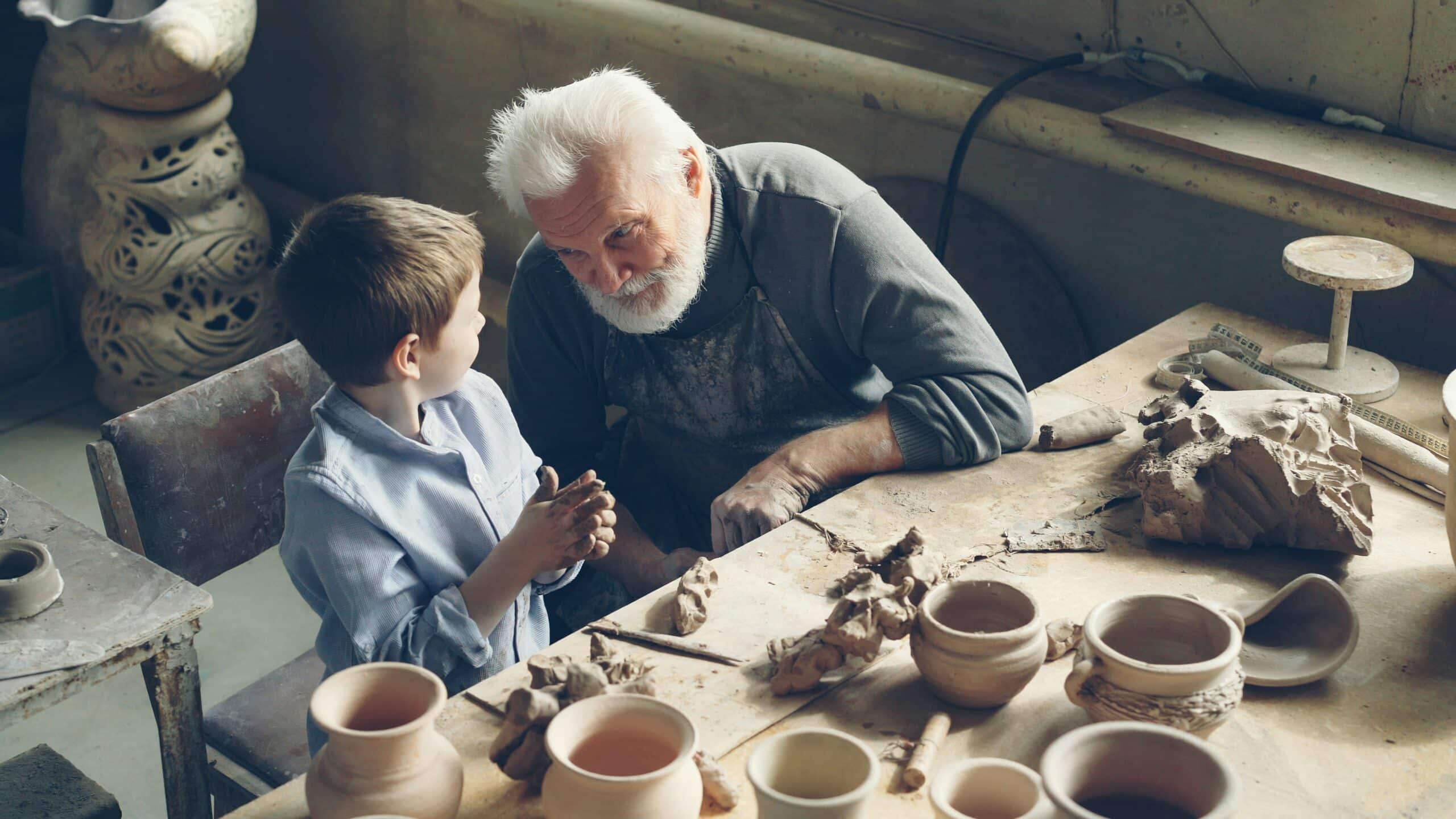A photo of an older man and younger boy doing pottery together